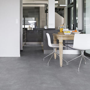 donkergrijze tegelvloer met subtiele betonstructuur en matte afwerking, bestaande uit grote rechthoekige tegels in verschillende tinten antracietgrijs