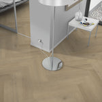 licht eiken vloer in visgraatmotief met subtiele houtstructuur, moderne woonkamer met metalen vloerlamp en kleine witte bijzettafel met decoratie