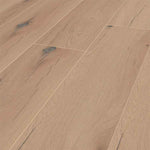 licht beige eiken vloer met brede planken en subtiele houtnerfstructuur, met enkele donkere noesten en lichte groeflijnen tussen de planken