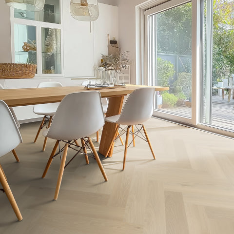 lichte eiken visgraatvloer met brede planken in een lichte, natuurlijke tint in een moderne eetkamer met witte stoelen en veel natuurlijk licht door schuifpui