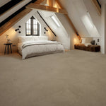 lichte beige tegelvloer met matte afwerking en subtiel onregelmatig structuurpatroon in een moderne slaapkamer met houten balken en wit beddengoed