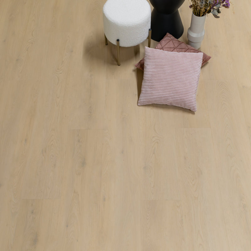 lichte beige eiken vloer met subtiele houtnerfstructuur en brede planken, met een wit gebogen poefje, zwarte vaas en zachte kussens in roze tinten en decoratieve drogende bloemen