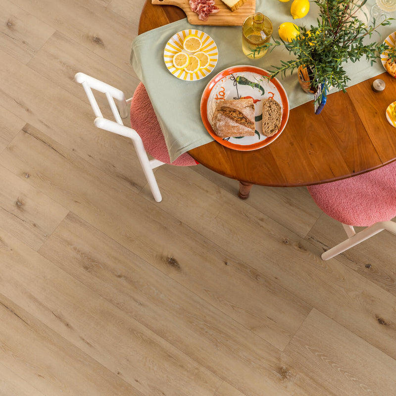licht eiken vloer met brede planken en natuurlijke houtstructuur onder een houten ronde tafel met servies en grijsgroene tafelloper