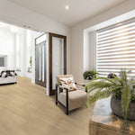 lichte beige eiken vloer met brede planken en een subtiele houtnerfstructuur in een moderne lichte woonkamer met beige fauteuil en planten op houten tafel
