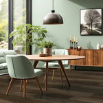 donkergrijze vloer met brede planken en subtiele houtstructuur in modern ingerichte eettafelomgeving met ronde houten tafel, mintgroene stoelen en houten dressoir tegen groene wand