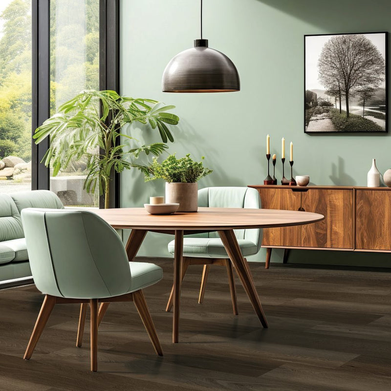 donkergrijze vloer met brede planken en subtiele houtstructuur in modern ingerichte eettafelomgeving met ronde houten tafel, mintgroene stoelen en houten dressoir tegen groene wand