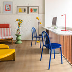 lichte eiken vloer met brede planken en subtiele houtstructuur in een modern interieur met blauwe metalen stoelen, gele vloerlamp, wit bureau met rood bureaulampje en kleurrijke wanddecoratie