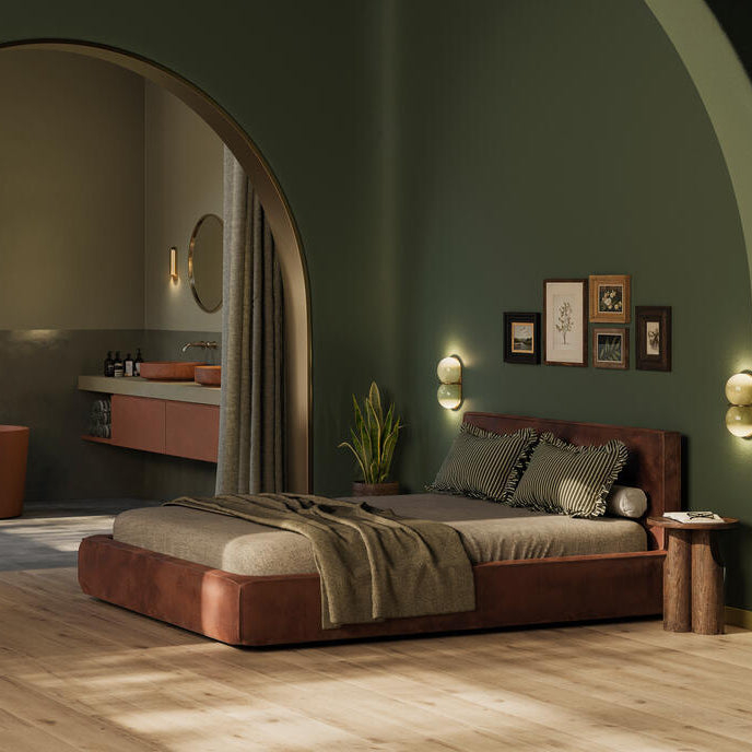 lichte beige eiken vloer met brede planken in rechte gelegd patroon in moderne slaapkamer met donkergroen geschilderde muren en rustbruin leren laag bed met gestreepte kussens