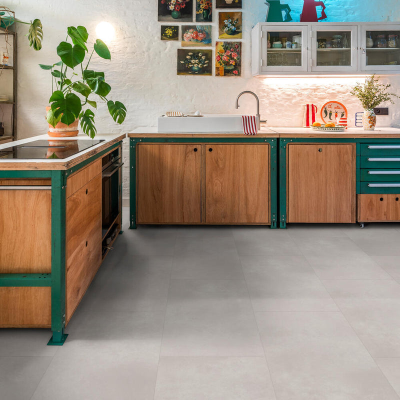 lichte tegelvloer met grote matte tegels in asgrijs kleur met subtiel golvend streeppatroon in moderne keukenomgeving met houten kastfronten en groene metalen accenten