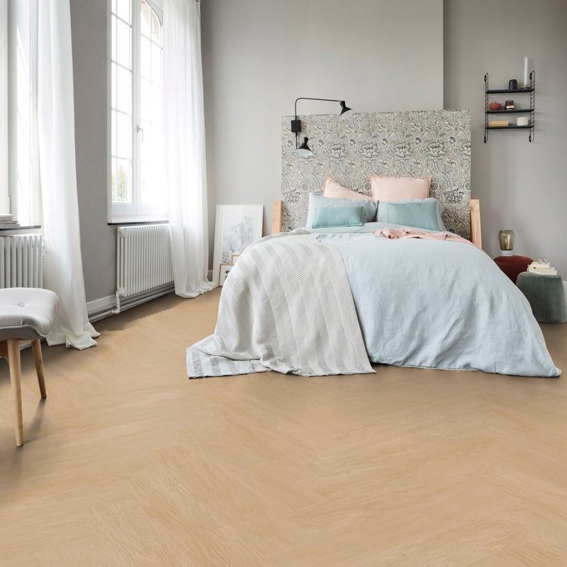 lichte eiken visgraatvloer met fijne houtstructuur in een slaapkamer met lichtgrijze muren en pastelgekleurde accenten in beddengoed en kussenhoesjes
