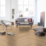 lichte eiken visgraatvloer met een subtiele houtstructuur in een modern, licht ingericht interieur met grijze bank en zwarte metalen stoel